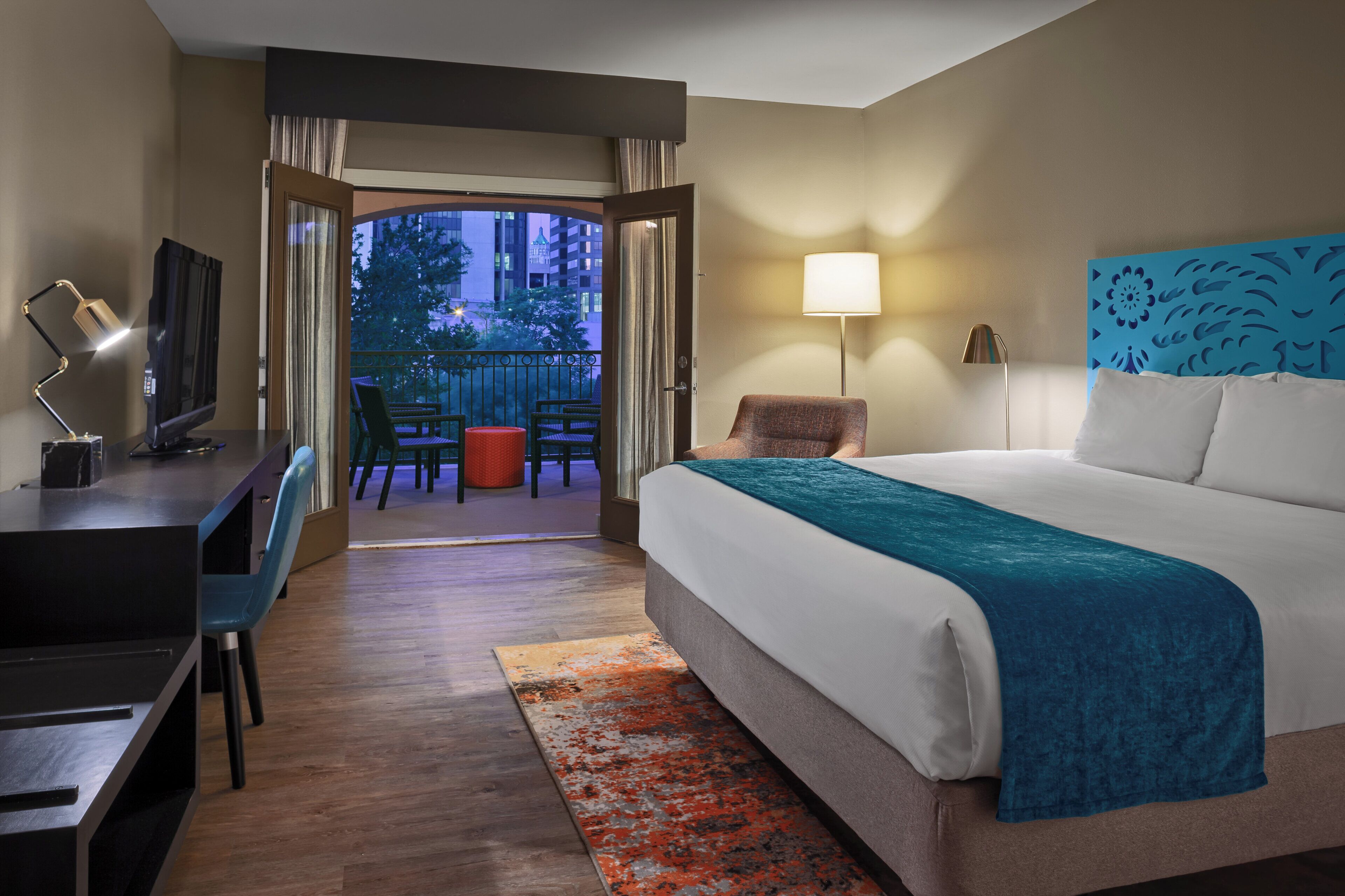 Ein Hotelzimmer mit Bett, Schreibtisch, Stuhl und Blick ins Freie.