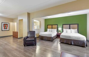 A hotel room with two beds, a chair, a dresser, and a mirror.