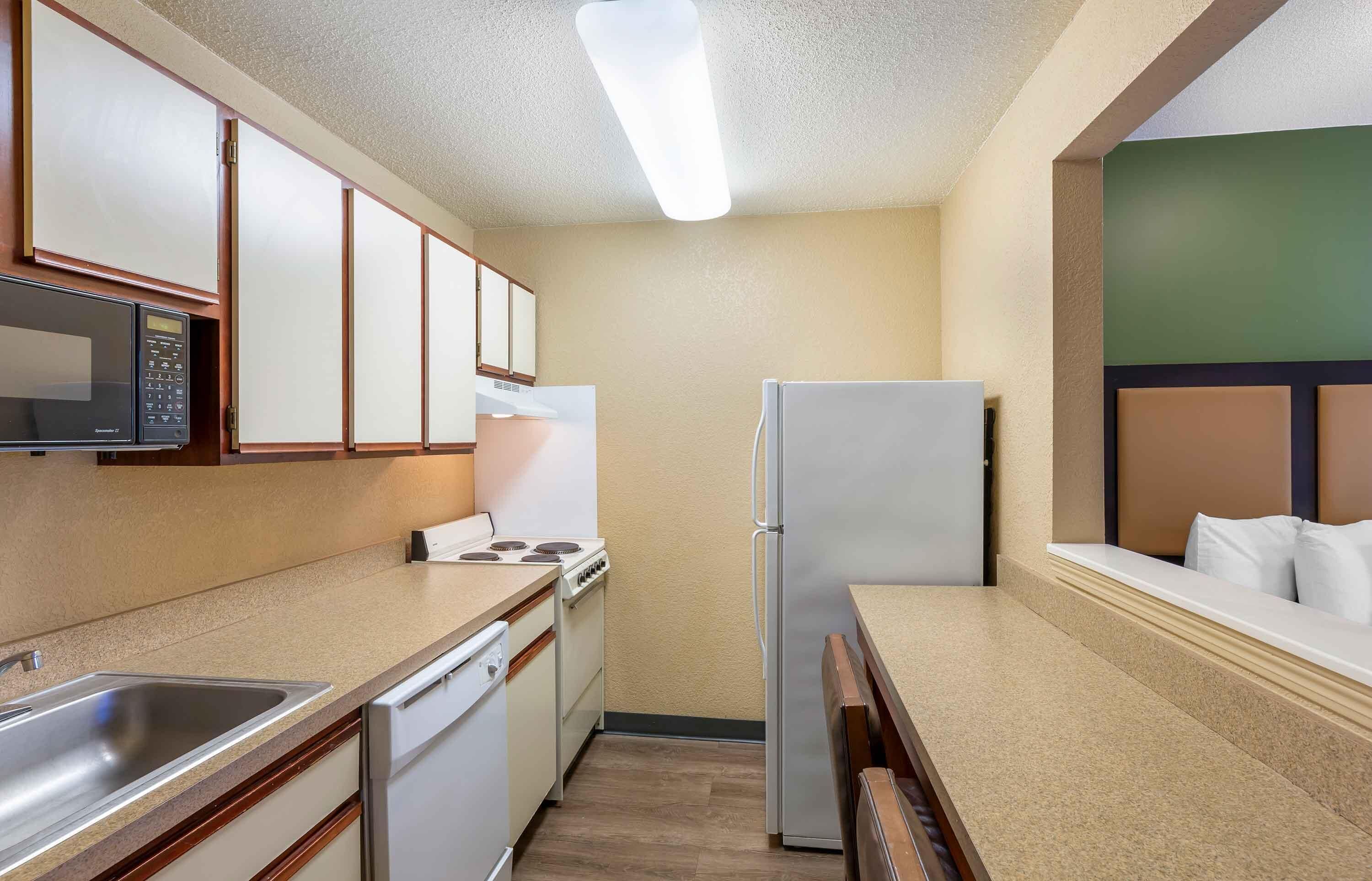 Una cocina compacta con microondas, estufa, refrigerador y pileta.