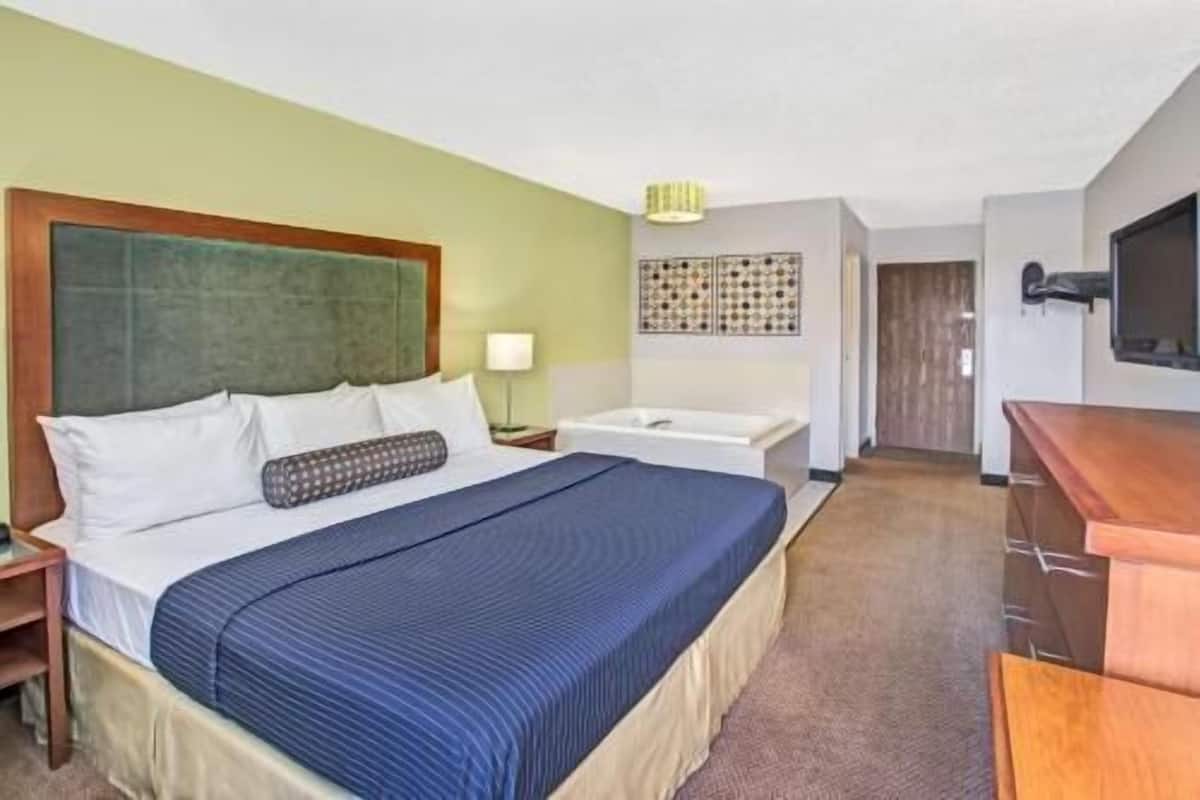 A hotel room with a bed, a desk, a chair, a TV, and a bathroom.