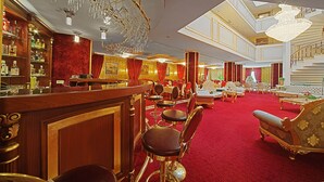 Un elegante vestíbulo de hotel con alfombra roja, mobiliario sofisticado y una zona de bar con copas.