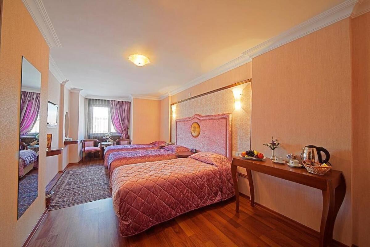 A hotel room with two beds, a desk, and a mirror.