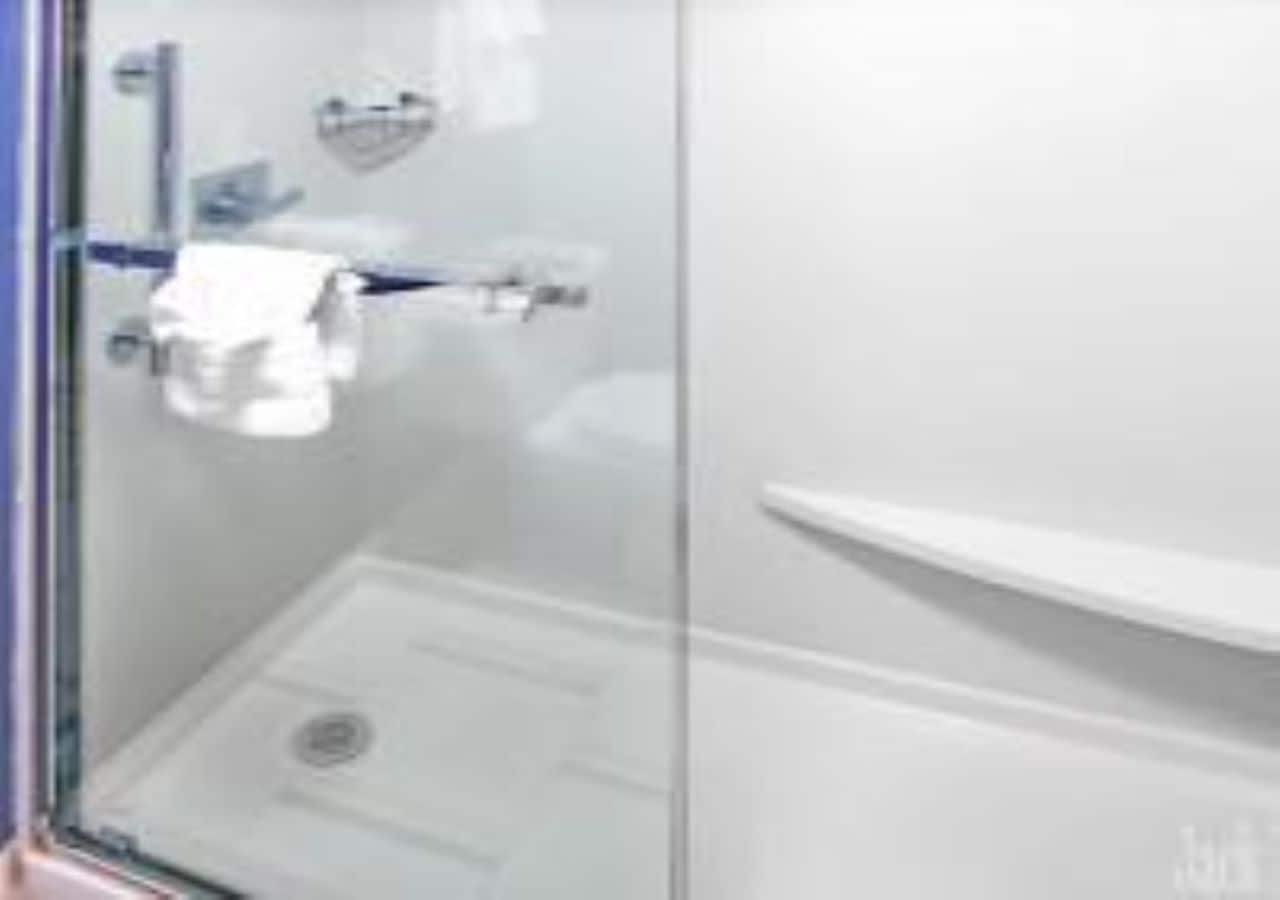 Un bany modern amb un plat de dutxa de vidre, un lavabo blanc i una barra de tovalloles.