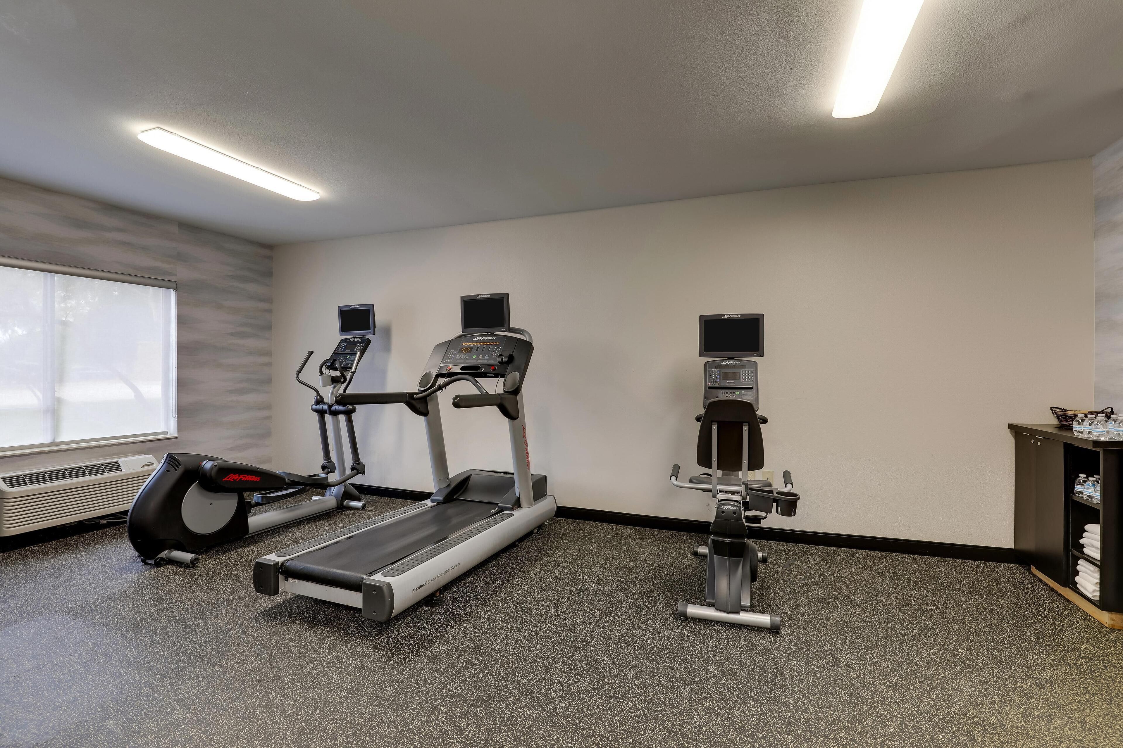 Une salle de sport équipée de tapis de course, d’un vélo d’appartement et d’un rameur.