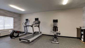 Un gimnasio con cintas de correr, una bicicleta estática y una máquina de remo.