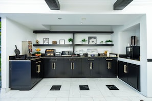 Una cocina moderna con armarios negros, tiradores dorados y salpicadero blanco.