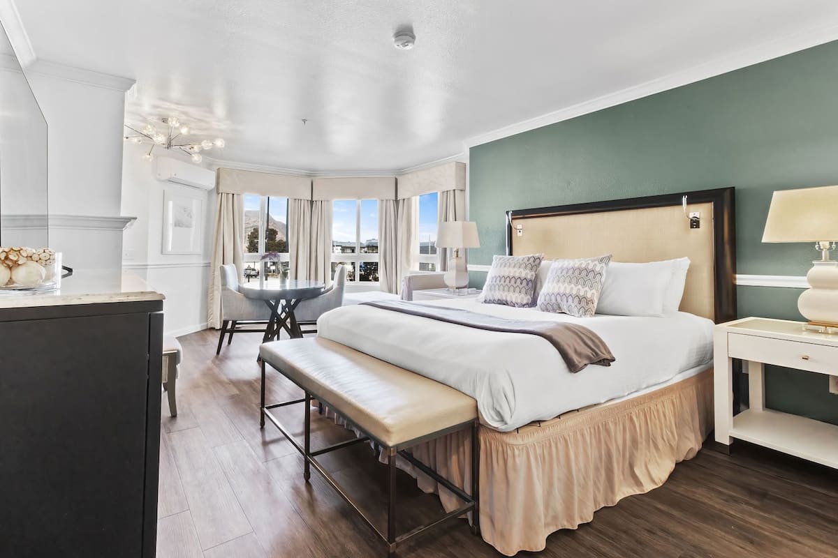 A hotel room with a large bed, a desk, a chair, and a view of the outdoors.