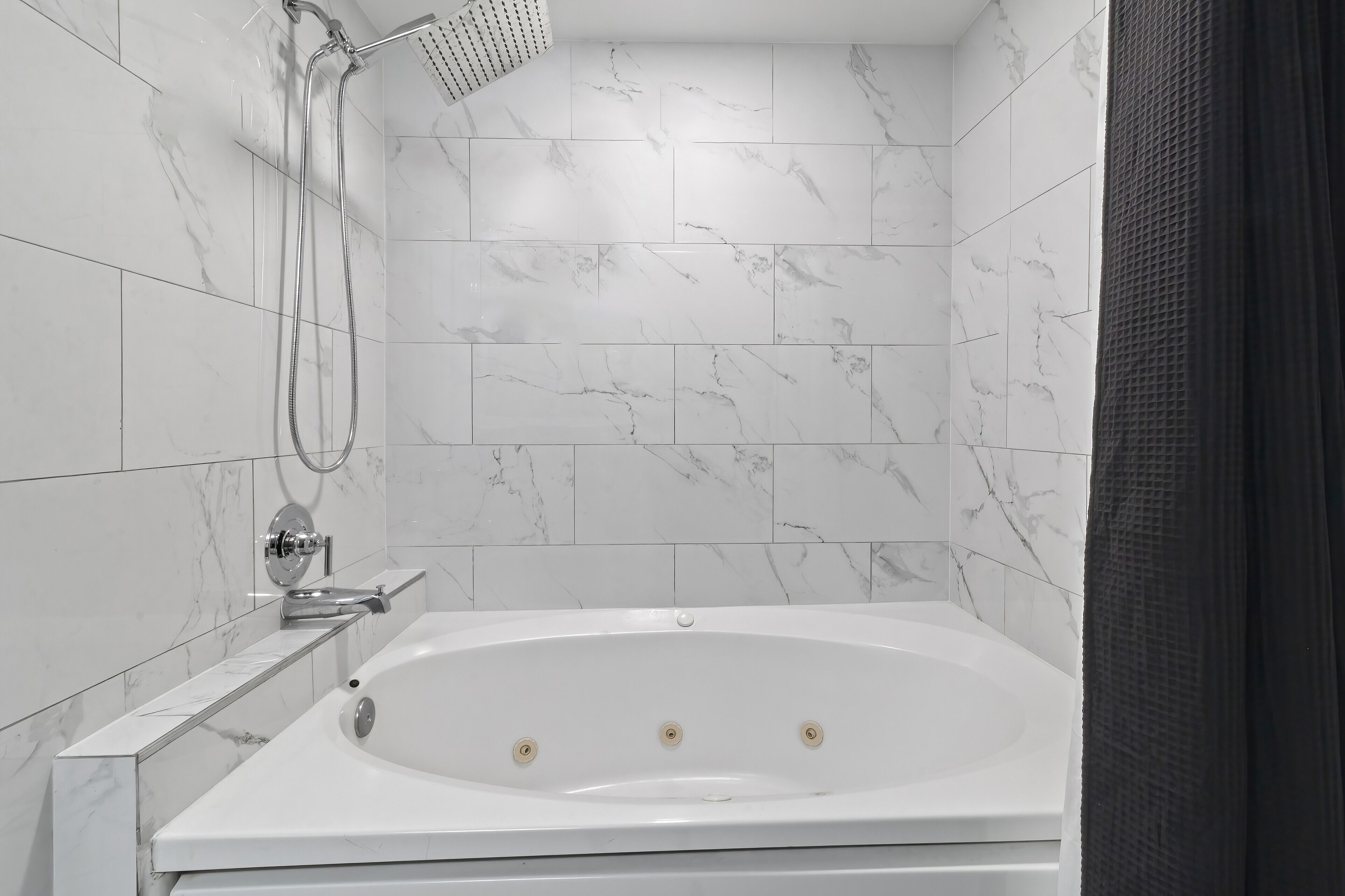 Un baño moderno con una bañera independiente, un cabezal de ducha de mano y un grifo empotrado.