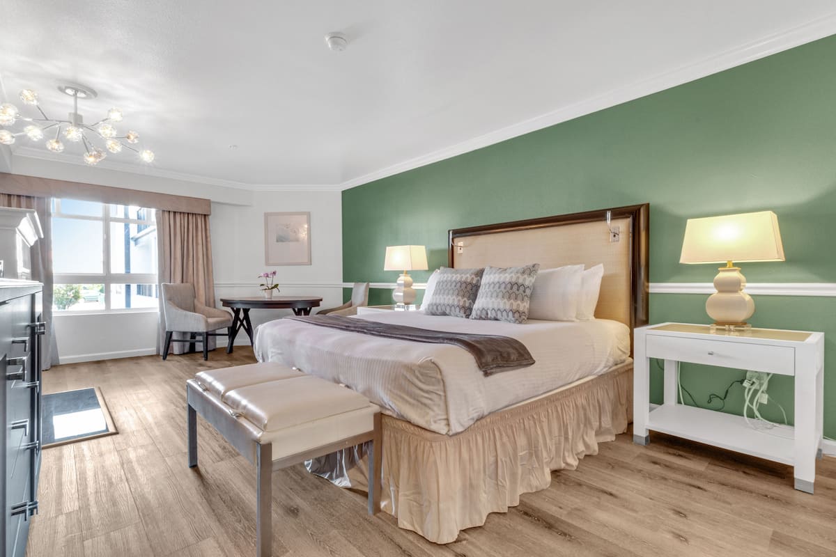 A neatly arranged bedroom with a large bed, bedside tables, a desk, and a chair.