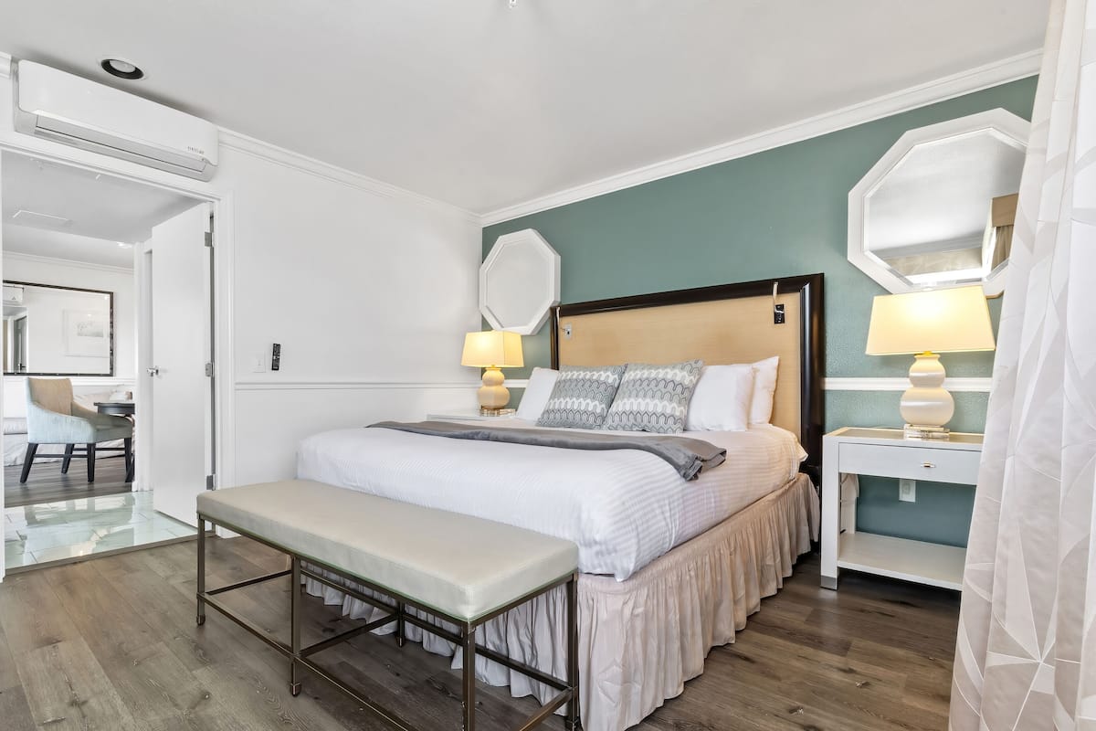 A bedroom with a bed, bedside tables, a bench, and a mirror.