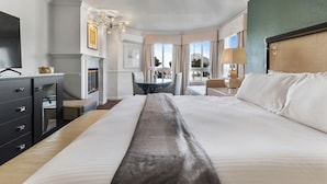 Habitación de hotel con una cama grande, un escritorio, una silla, un televisor y una chimenea.
