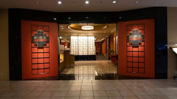 A hotel lobby with a modern design, featuring a reception desk, a chandelier, and a patterned wall.