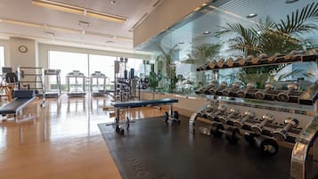 A modern gym with treadmills, weight machines, and a bench.
