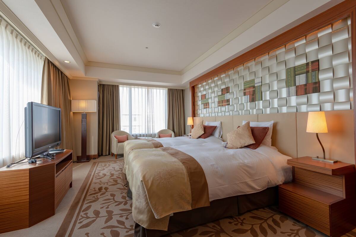 Une chambre d’hôtel avec un grand lit, une télévision, un bureau avec une lampe et une tête de lit décorative.