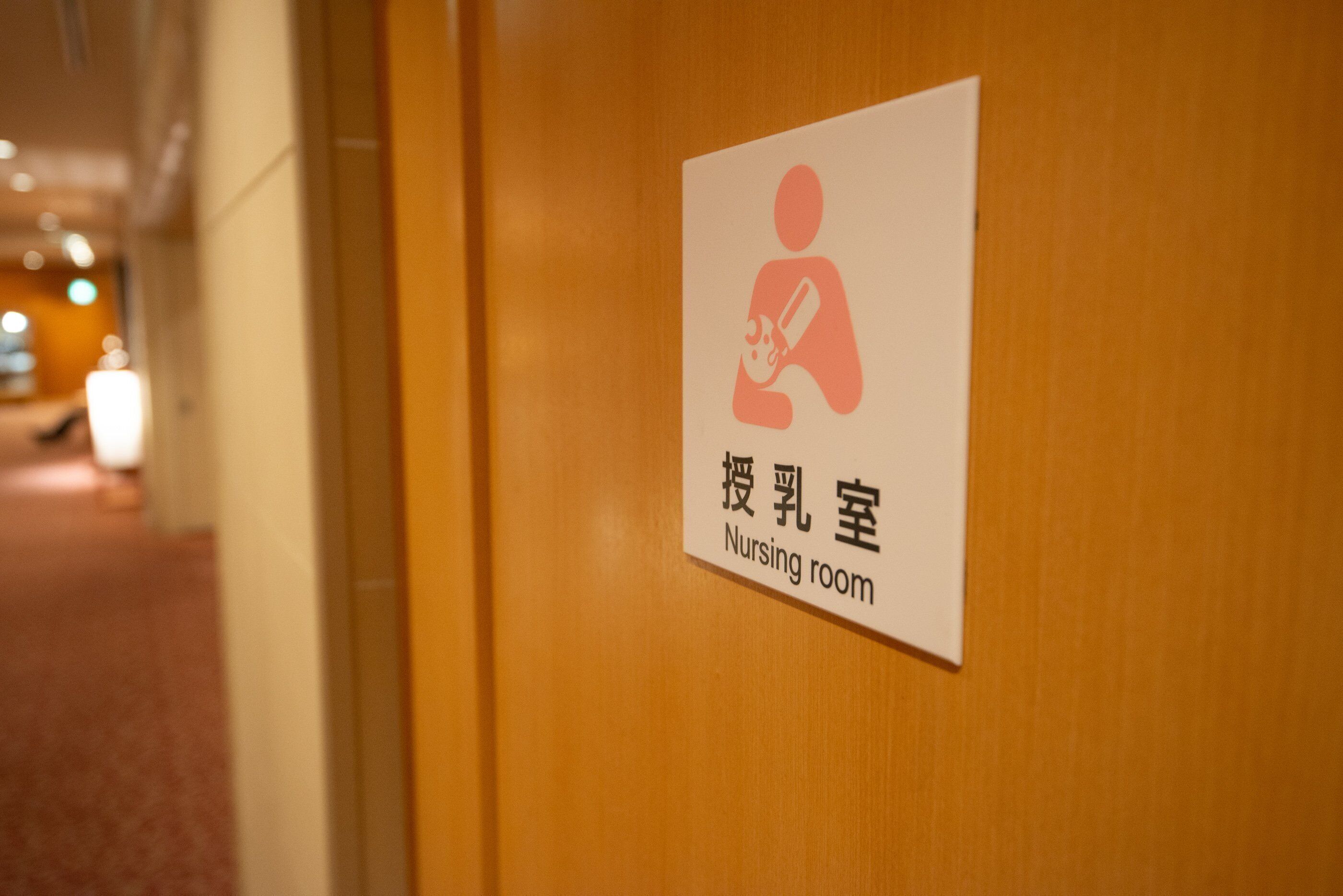 A sign indicating a nursing room with a figure holding a baby.