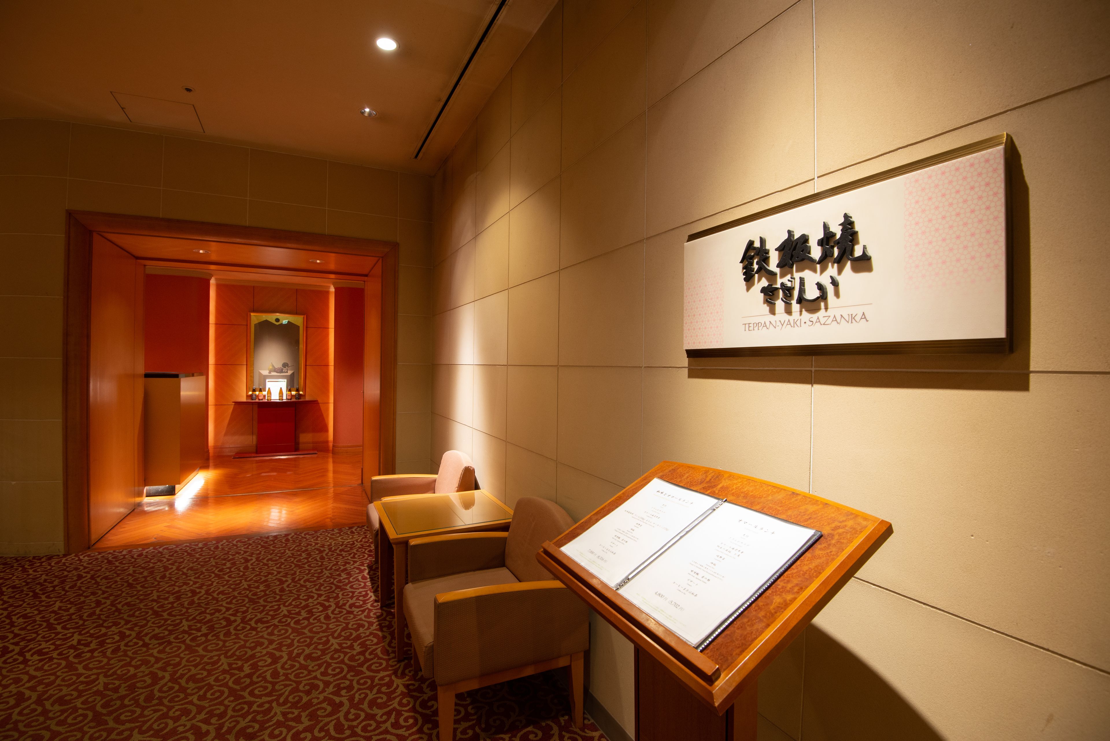 A hotel lobby with a reception desk, seating area, and a wall-mounted sign.