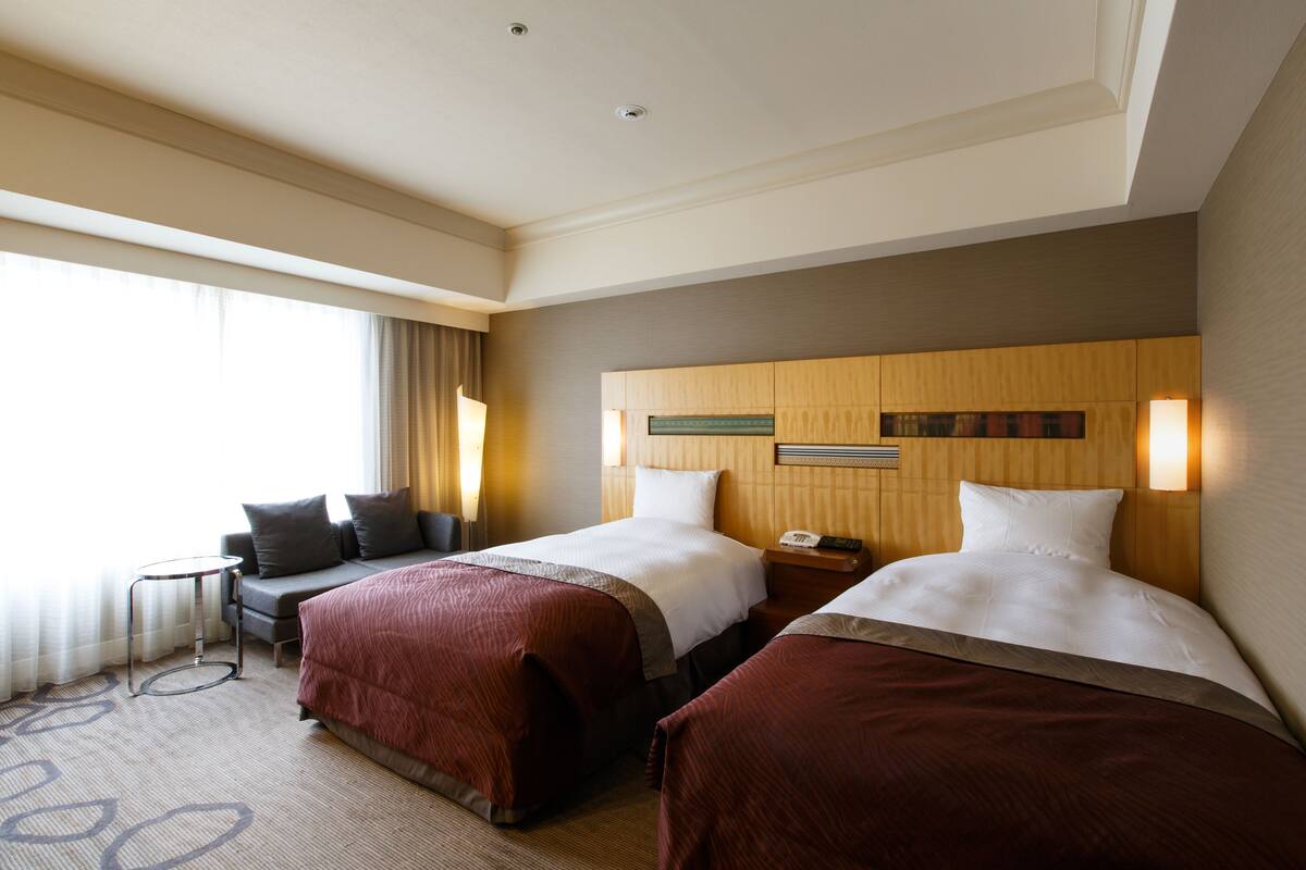 Une chambre d’hôtel avec deux lits, un canapé, une petite table et une table de chevet.