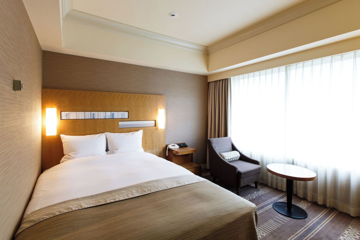 Une chambre d’hôtel avec un grand lit, un bureau, une chaise et une petite table.