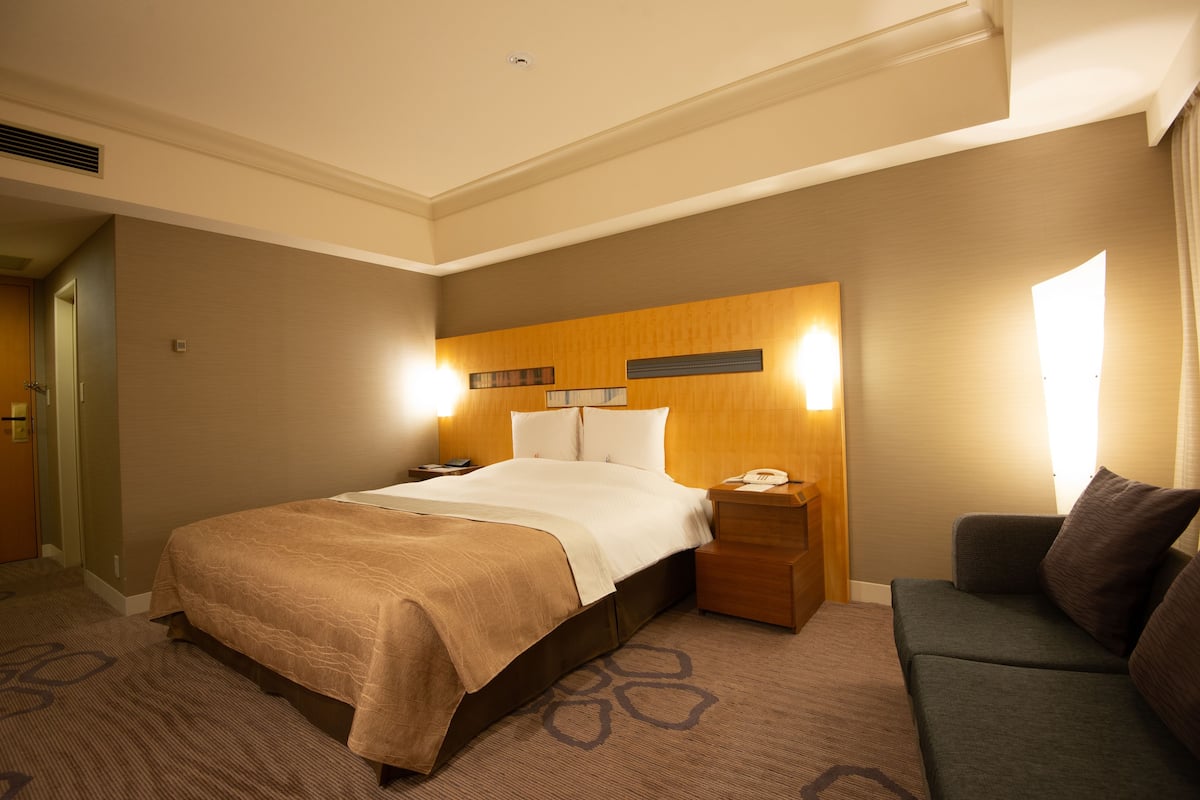 Une chambre d’hôtel avec un grand lit, une table de chevet, une commode et un canapé.