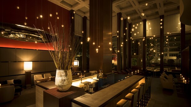 A modern bar area with a long counter, seating, and hanging lights. - Hotel Okura Fukuoka (Fukuoka)