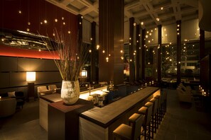 A modern bar area with a long counter, seating, and hanging lights. - Hotel Okura Fukuoka (Fukuoka)