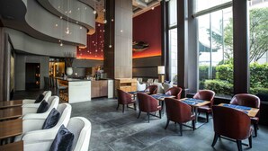 A modern hotel lobby with a bar area, seating arrangements, and large windows offering views of the outdoors. - Hotel Okura Fukuoka (Fukuoka)