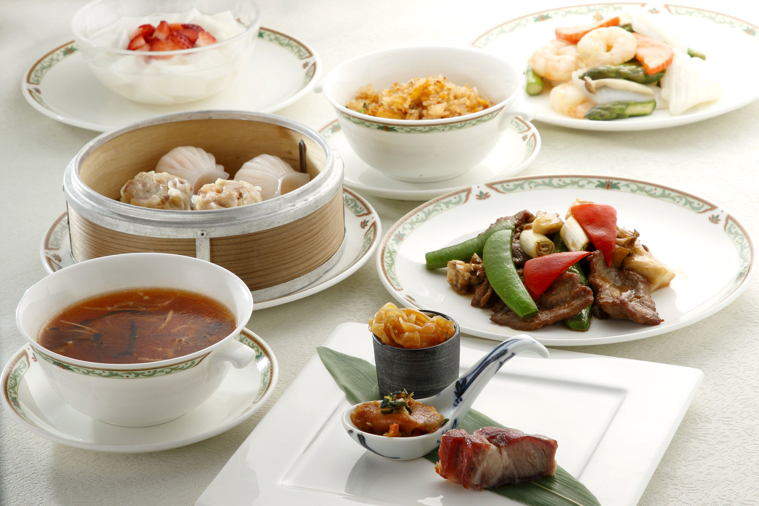 A variety of dishes including soup, dumplings, and stir-fried vegetables on a table.