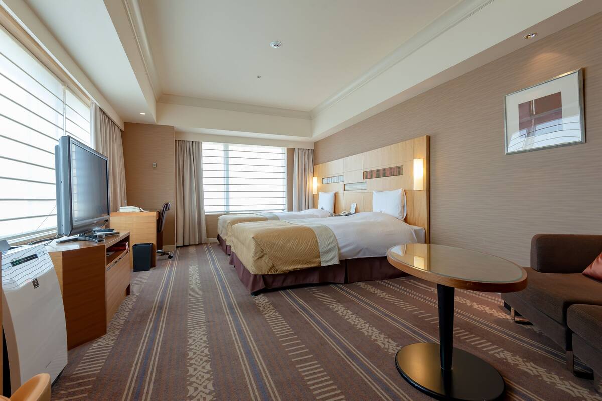 Une chambre d’hôtel avec un grand lit, un bureau avec une télévision, une petite table et un canapé.