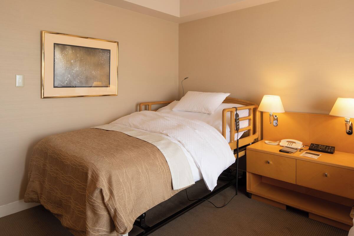 Une chambre d’hôtel avec un lit, une table de chevet, une lampe, un téléphone et un tableau encadré au mur.