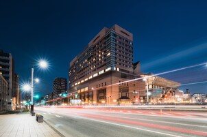 A modern hotel with a prominent glass facade, multiple floors, and a distinctive rooftop structure.