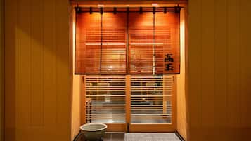 A traditional Japanese room with sliding doors, a tatami mat entrance, and a small table with a bowl.