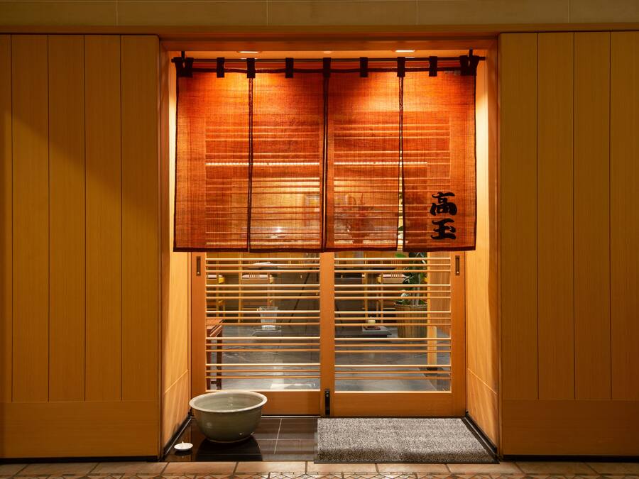 A traditional Japanese room with sliding doors, a tatami mat entrance, and a small table with a bowl.