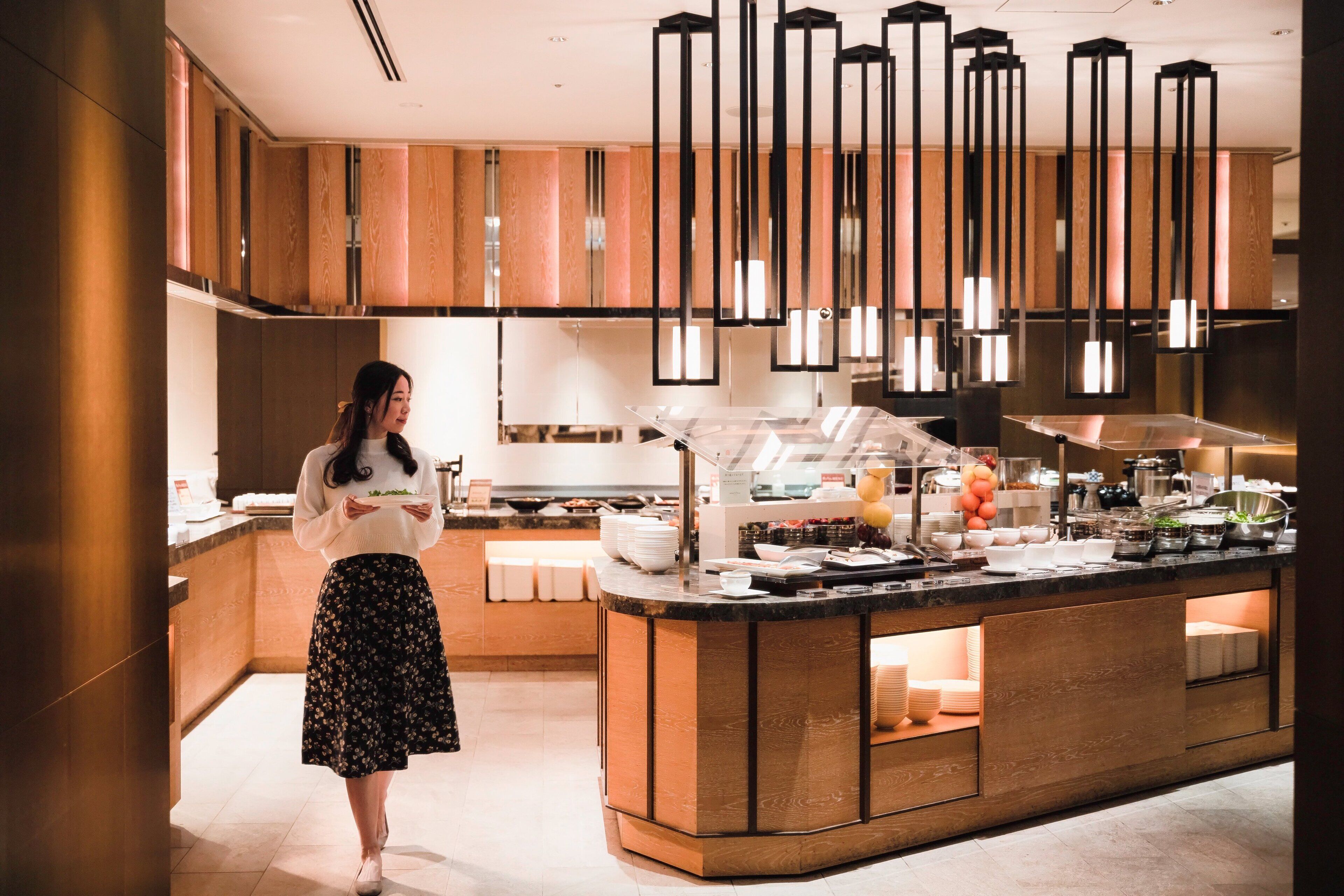 A modern kitchen with a central island, wooden cabinets, and pendant lighting.