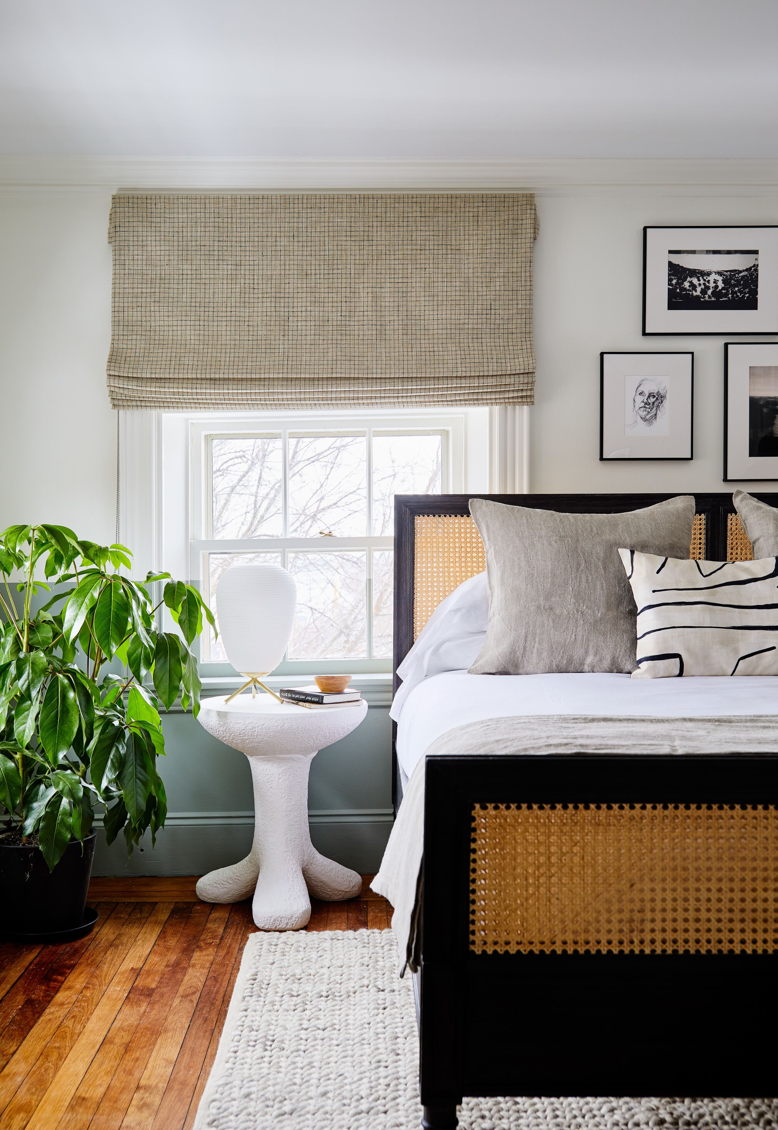 Une chambre avec un lit, une fenêtre donnant sur un beau paysage, une plante et une petite table.