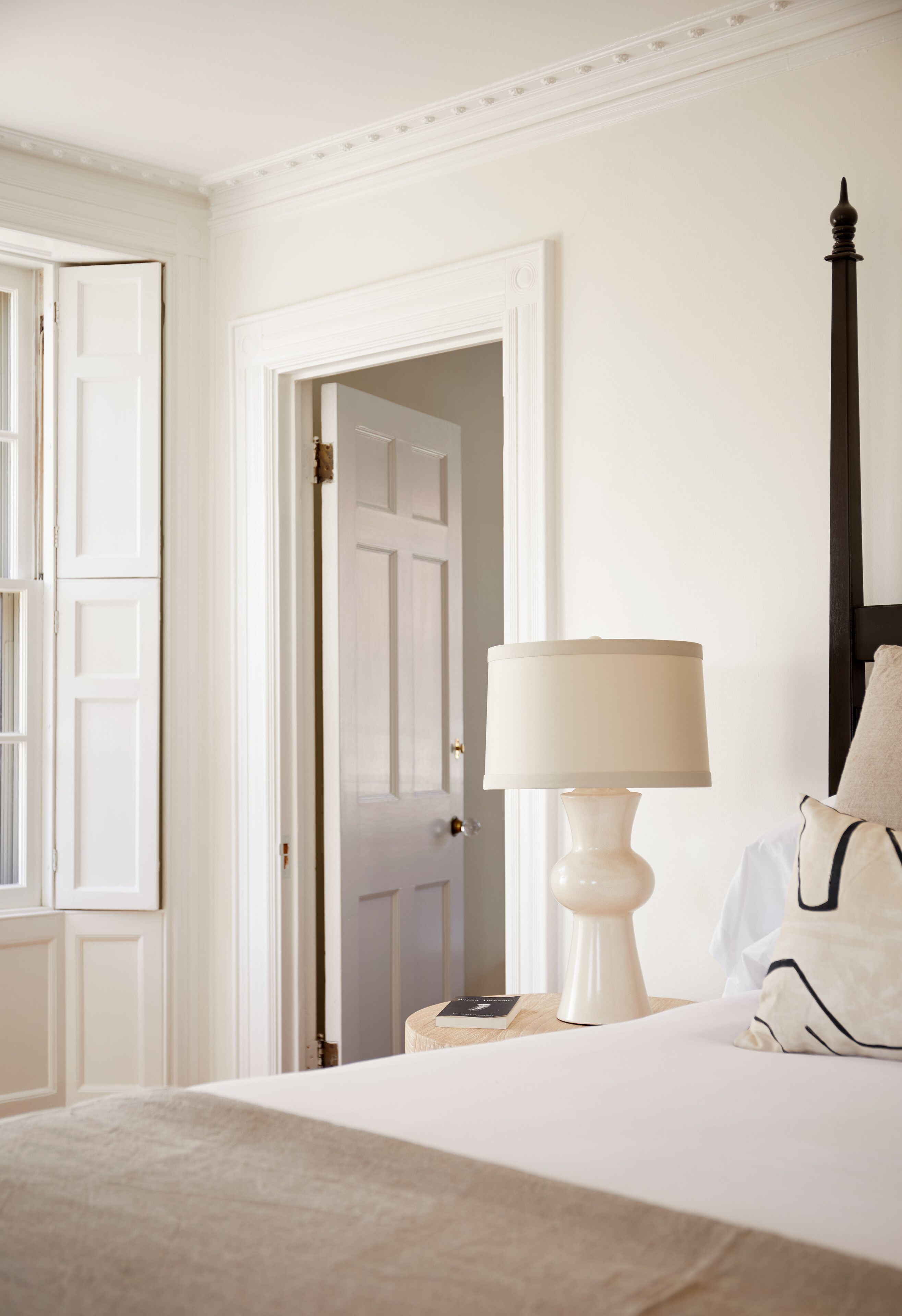 Een slaapkamer met een bed, een bedlampje en een deur naar een andere kamer.