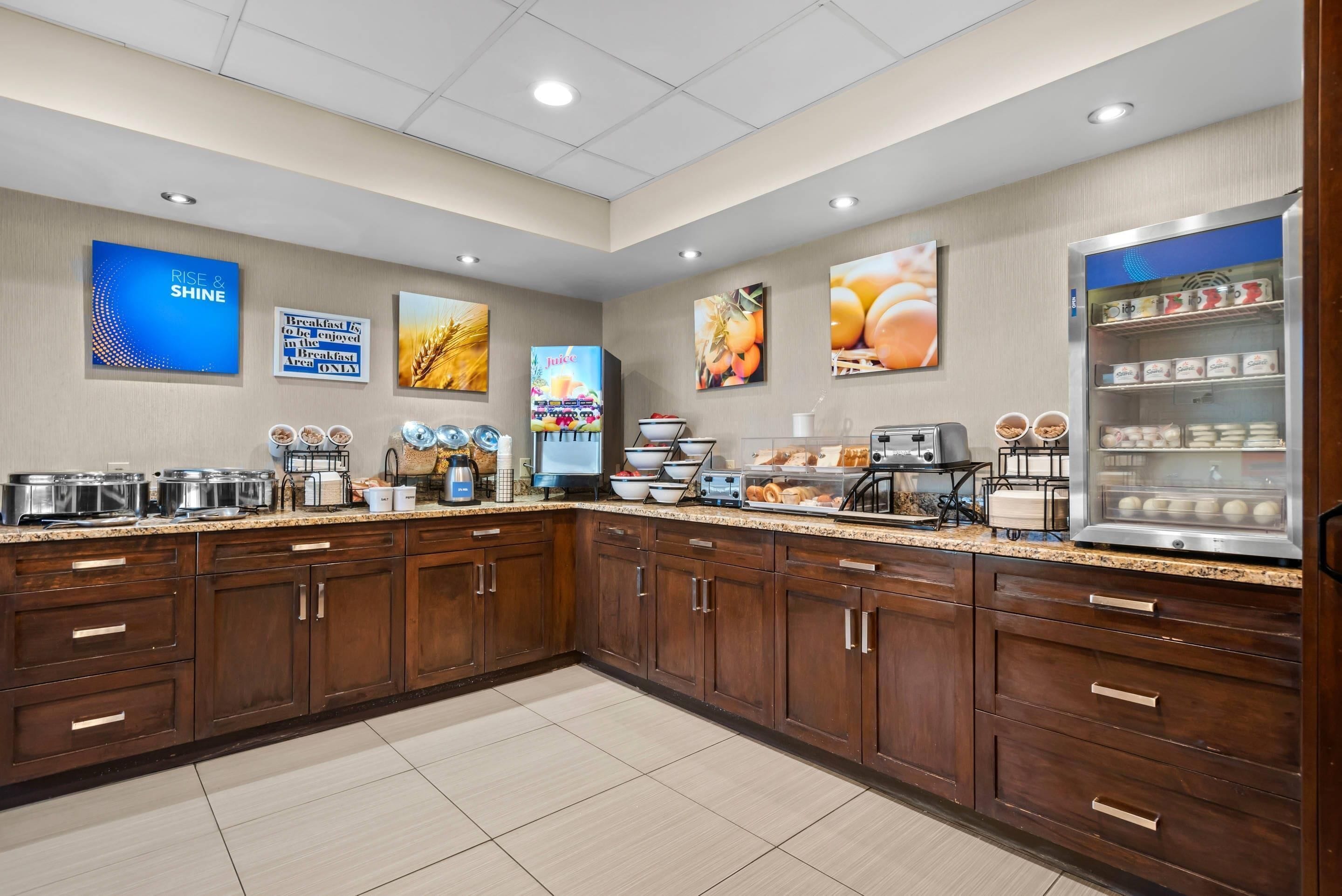 A modern kitchen with a granite countertop, stainless steel appliances, and a refrigerated display case.