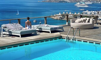 Una piscina al aire libre, sombrillas, tumbonas