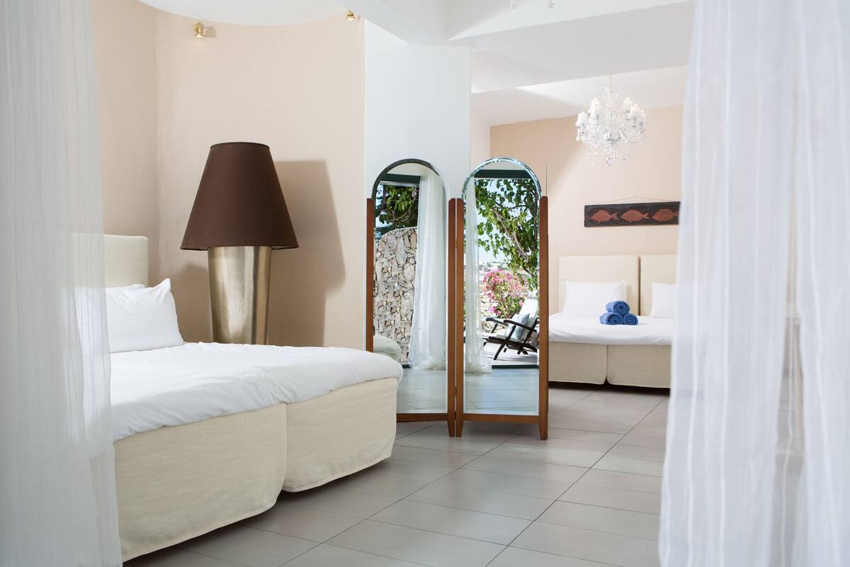 A hotel room with a bed, a lamp, a mirror, and a view of the outdoors.