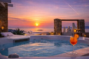 A luxurious outdoor hot tub area with a sunset view, stone pillars, and lounge chairs. - Tharroe of Mykonos (Mykonos)
