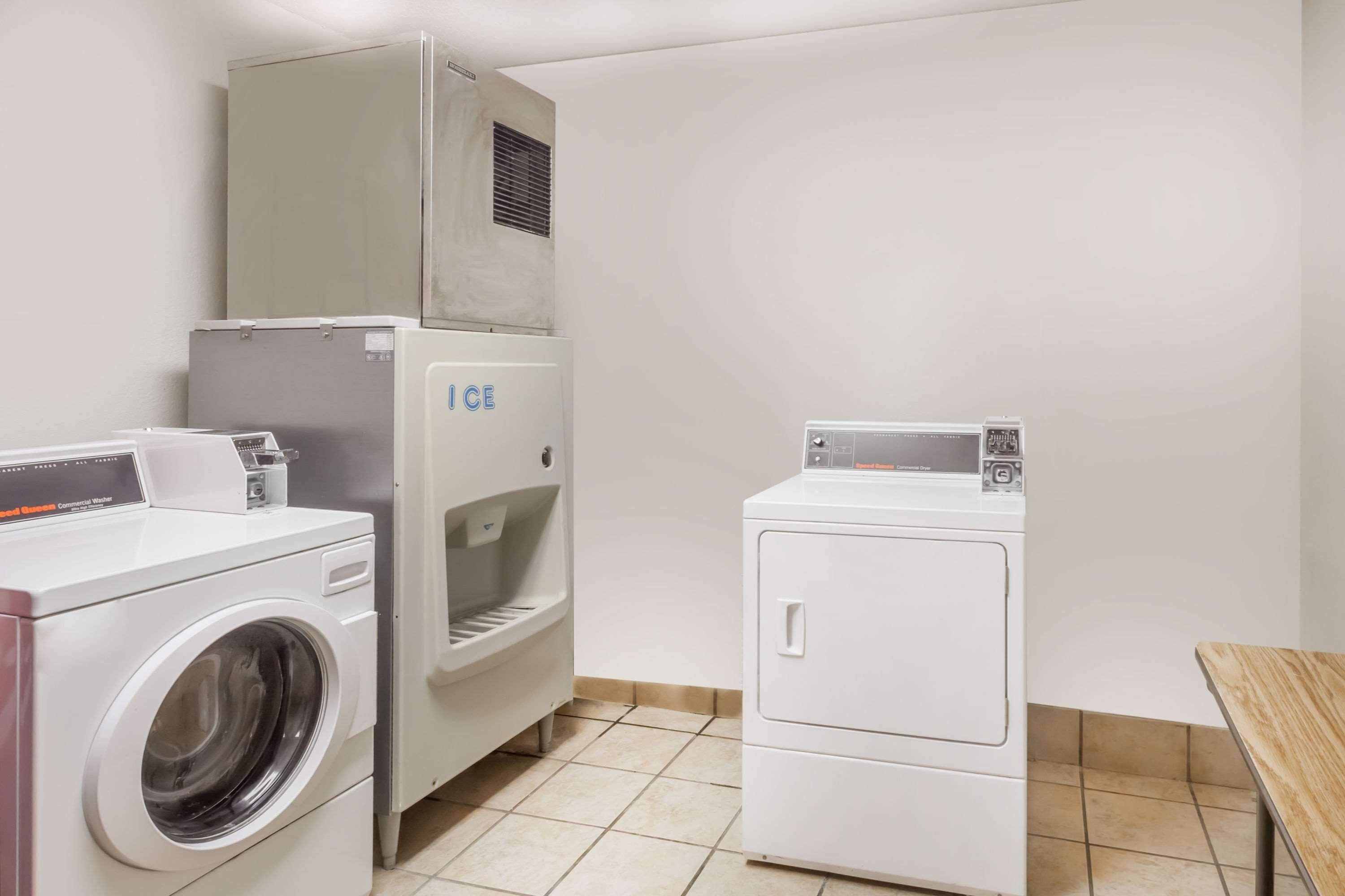 Un espace buanderie comprenant un lave-linge, un sèche-linge et un appareil à glaçons.
