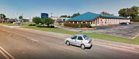 A parking lot with a building that has a blue roof and a sign that reads "Baymont."