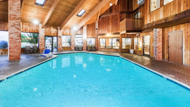 A large indoor swimming pool with wooden walls and a high ceiling. - Baymont by Wyndham Jackson (Jackson)