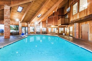 A large indoor swimming pool with wooden walls and a high ceiling. - Baymont by Wyndham Jackson (Jackson)