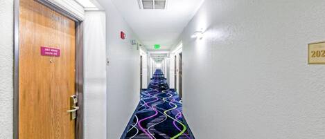 A hotel hallway with a patterned carpet, a door labeled "James Monroe Executive Suite," and an exit sign.