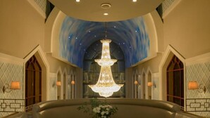 Eine luxuriöse Lobby mit einem prächtigen Chandelier, einem runden Tisch mit Blumen und einer gebogenen Sitzgruppe.