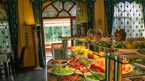 Ein reichhaltiges Buffet mit verschiedenen Speisen, eine Glastheke und ein Blick ins Freie durch ein Fenster.