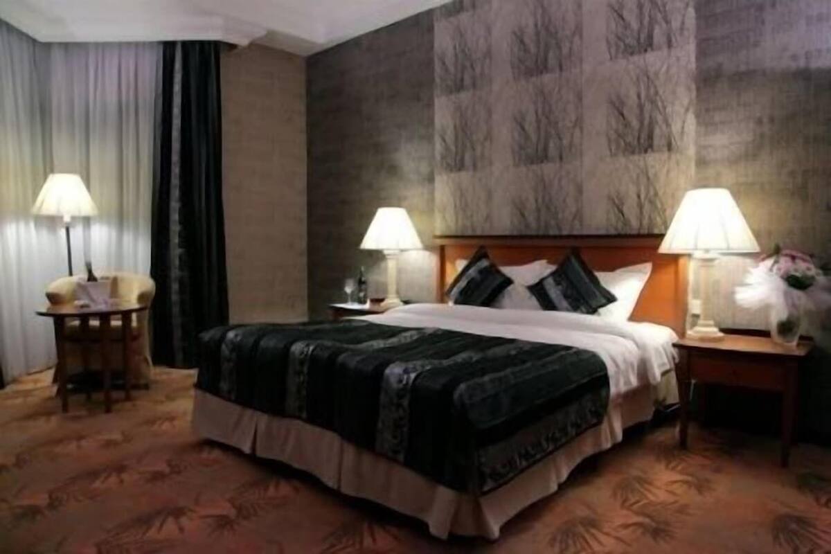 A hotel room with a bed, two bedside lamps, a nightstand, a chair, and a table.
