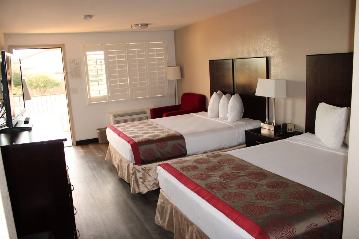 A hotel room with two beds, a desk, and a chair.