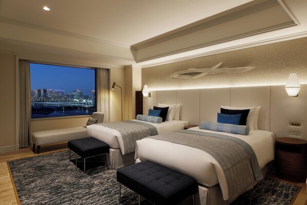 A hotel room with two beds, a bench, a view of a cityscape, and a large mirror. - Grand Nikko Tokyo Daiba (Tokyo)