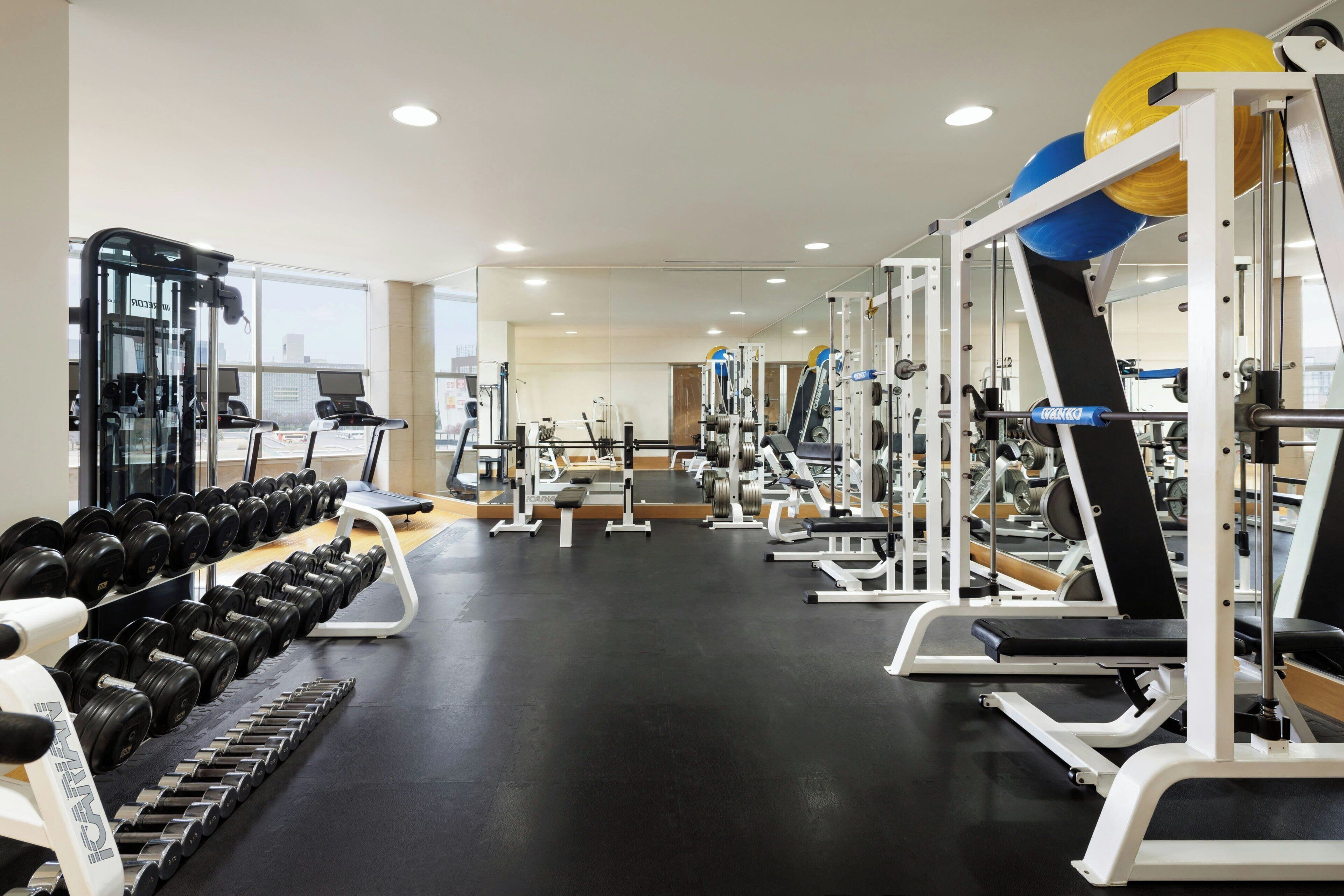 A gym with exercise equipment, treadmills, and weight racks.